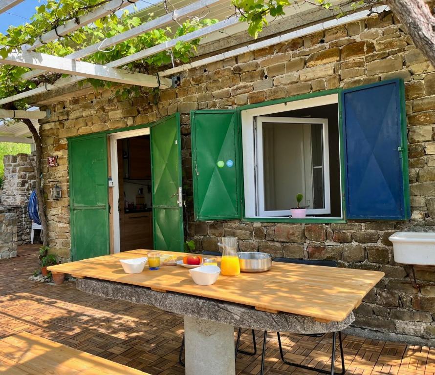 a wooden table in front of a stone building with a window at Olive Gardens Cottage above Portorož in Strunjan