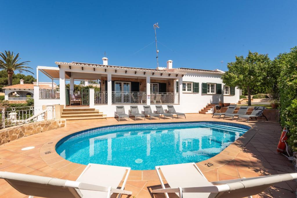 a villa with a swimming pool and chairs at Villa Maite by Escape Home in Binibeca