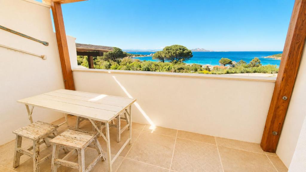 a table and two stools in a room with a window at Rena Bianca Residence 225 in Baja Sardinia