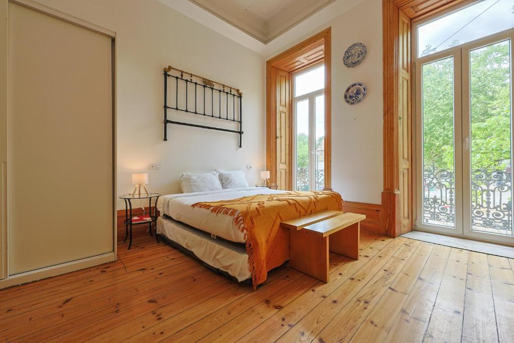 a bedroom with a bed and a large window at Casa da Praça by PURUS in Coimbra