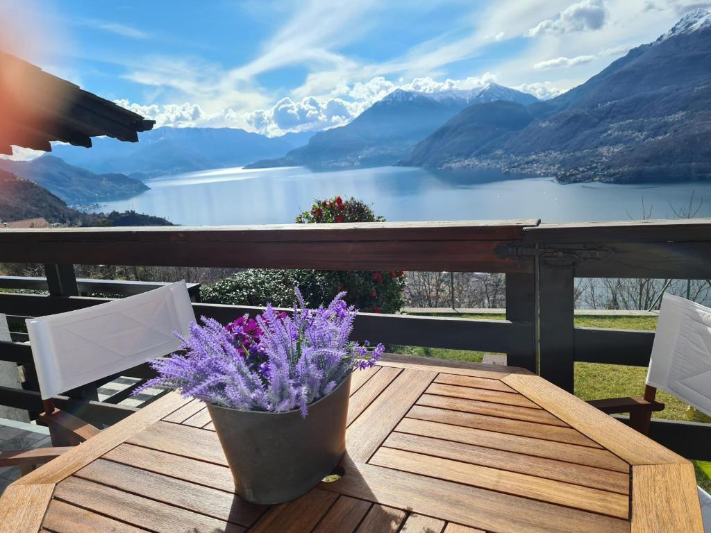 a table with purple flowers on a balcony with mountains at Lake Como - Incanto in Valvarrone