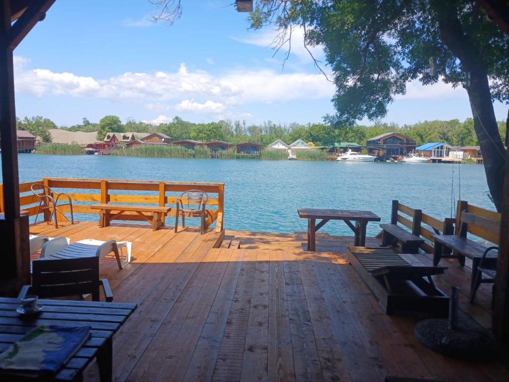 a wooden deck with benches and a table and water at Vikendica Eldar, Ada Bojana in Ulcinj
