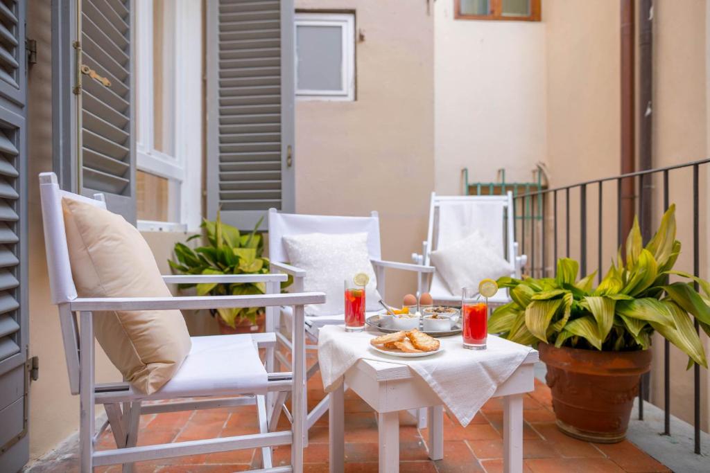 un patio con 2 sillas y una mesa con comida. en Novella White, en Florencia