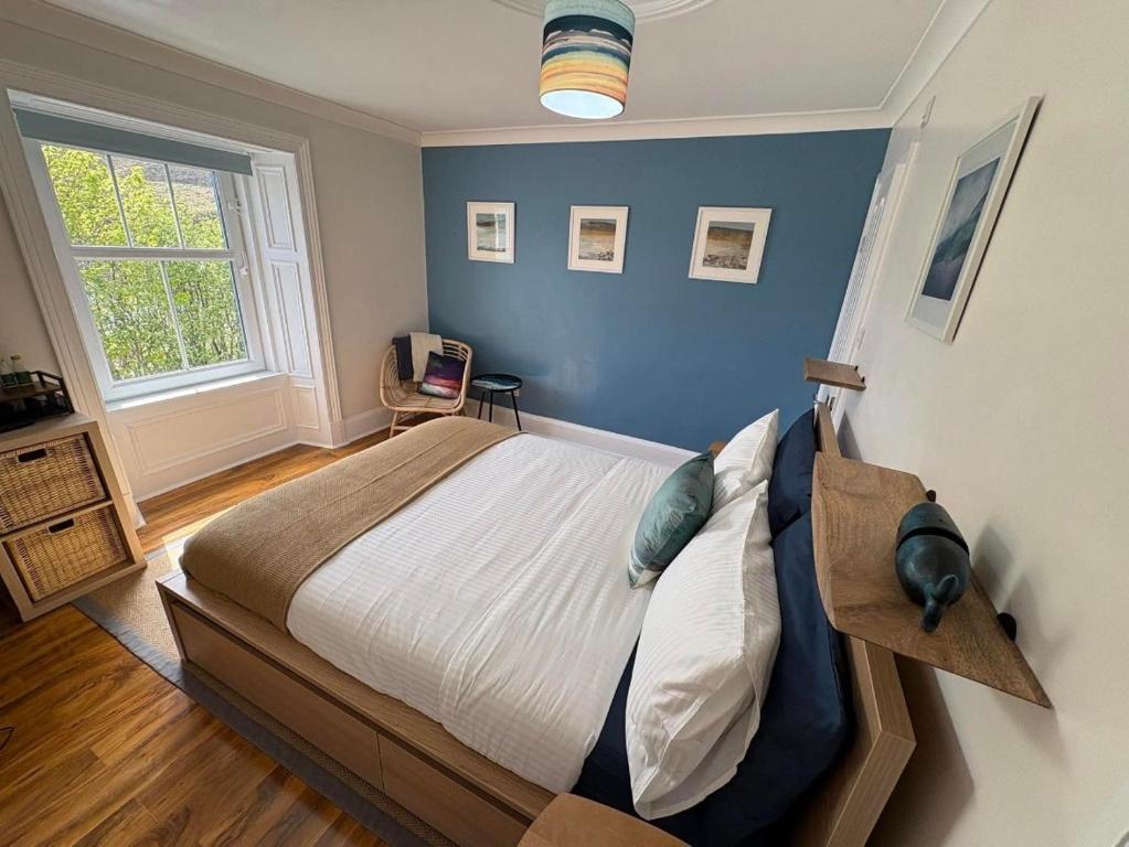 a bedroom with a large bed with a blue wall at Nook and Scranny in Tarbert