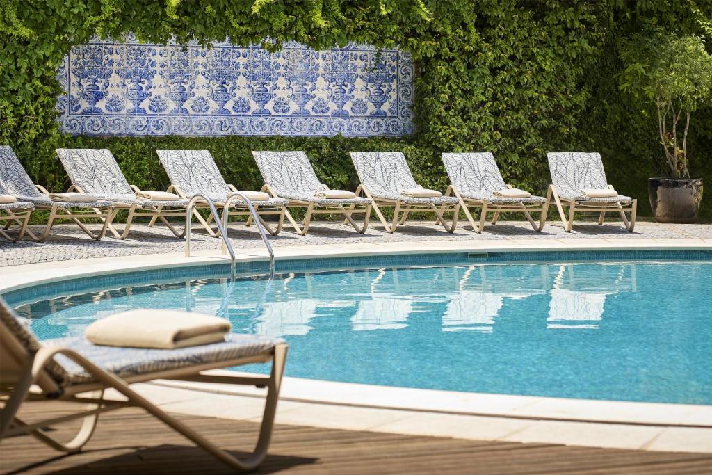 a row of lawn chairs next to a swimming pool at Avani Avenida Liberdade Lisbon Hotel in Lisbon