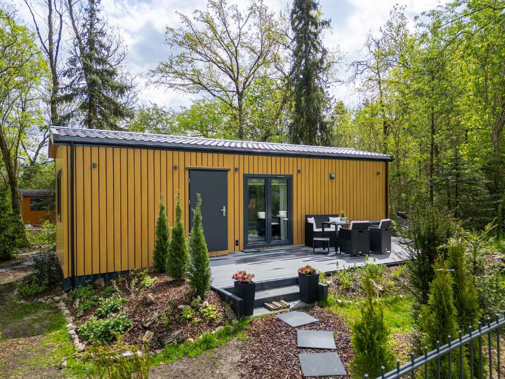 a yellow shed with a patio in a garden at Hygge Tiny House 1 - Berlin Brandenburg in Berlin