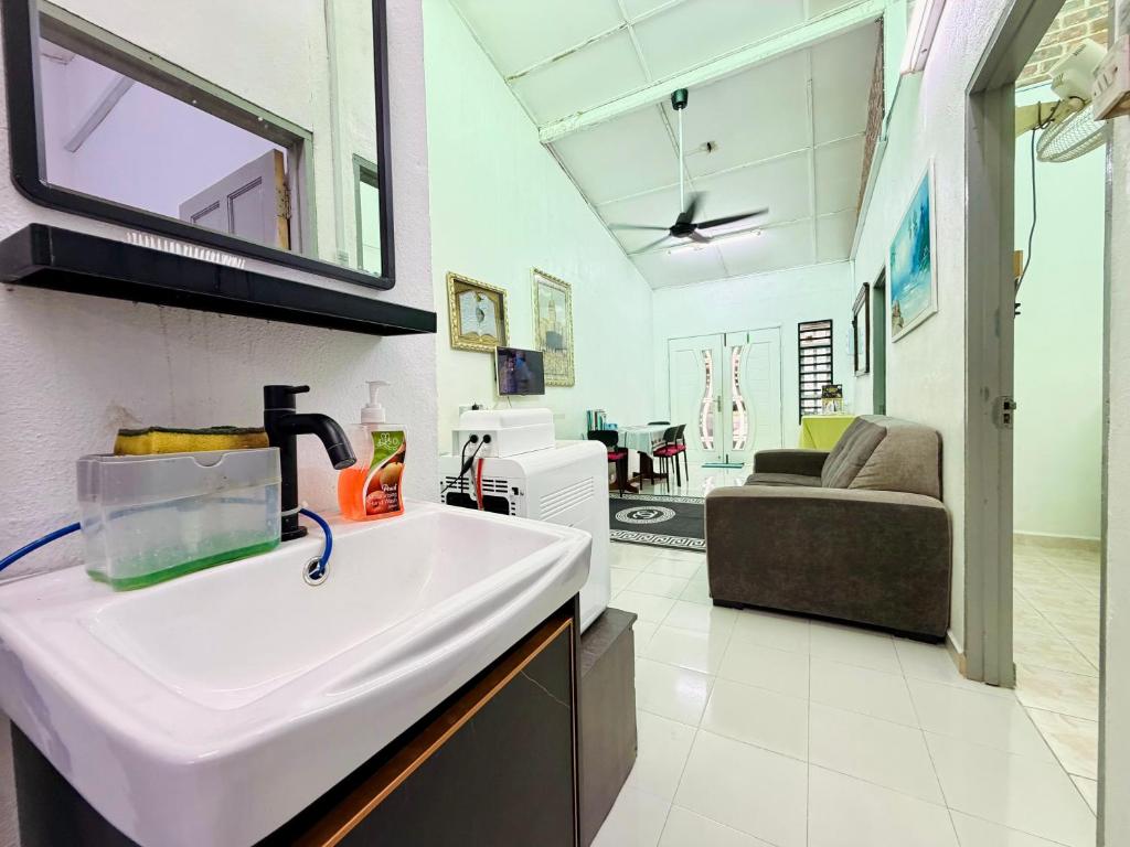 a bathroom with a sink and a living room at Lanang Islamic Homestay in Bedung