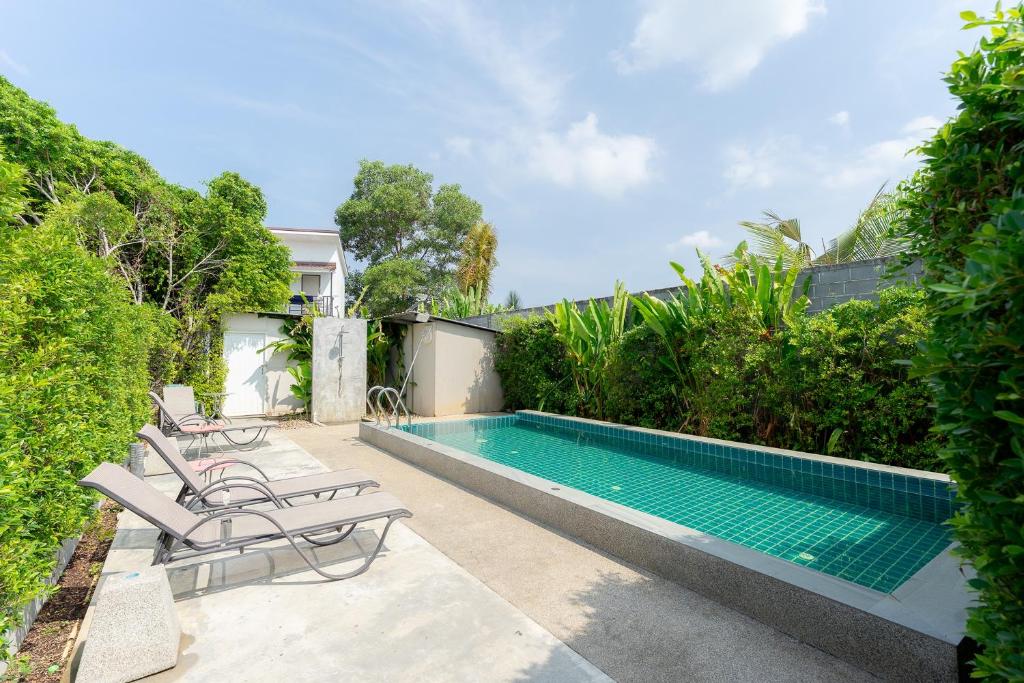 a swimming pool with lounge chairs next to a house at Malinee Resort in Bang Tao Beach