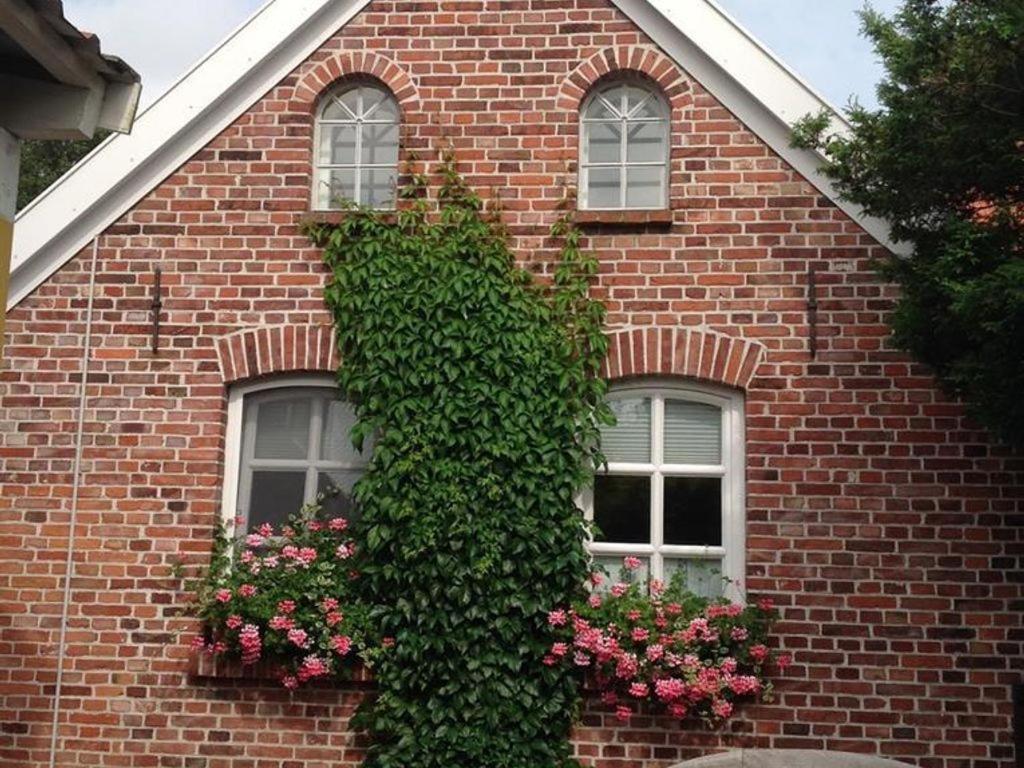 a brick building with two windows with flowers at Klaassen- Ferienhaus Up Warf in Emden
