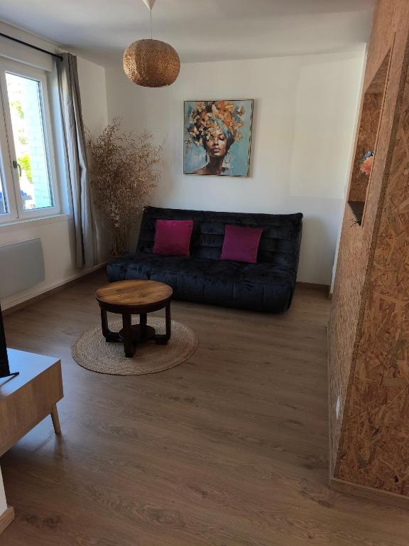 a living room with a black couch and a table at La maison du 116 in Gravelines