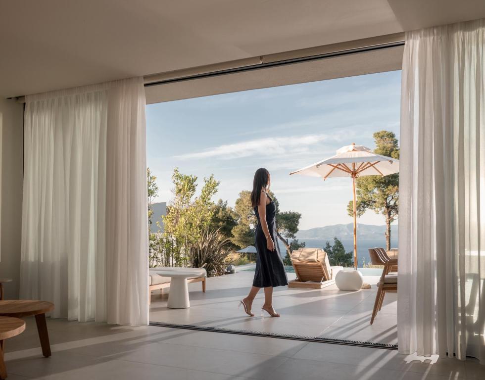 a woman walking in a living room looking out the window at Maritima Villas in Paliouri
