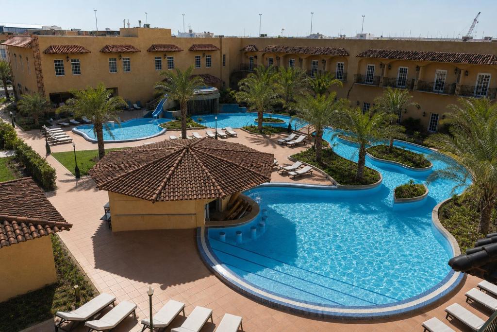 Draufsicht auf einen Pool mit Liegestühlen und einem Sonnenschirm in der Unterkunft Montrose - A Mayfair Collection Hotel in Kuwait