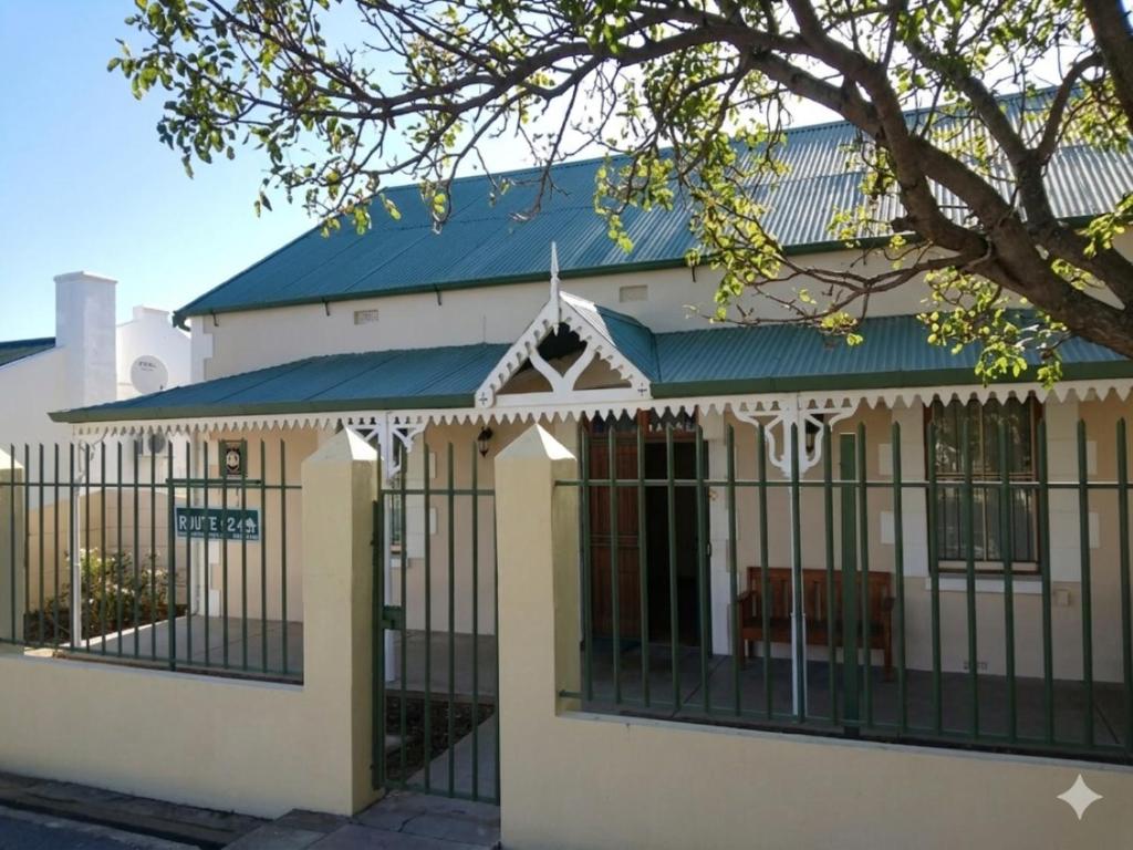 a white building with a blue roof and black fence at Route 62 B&B in Robertson