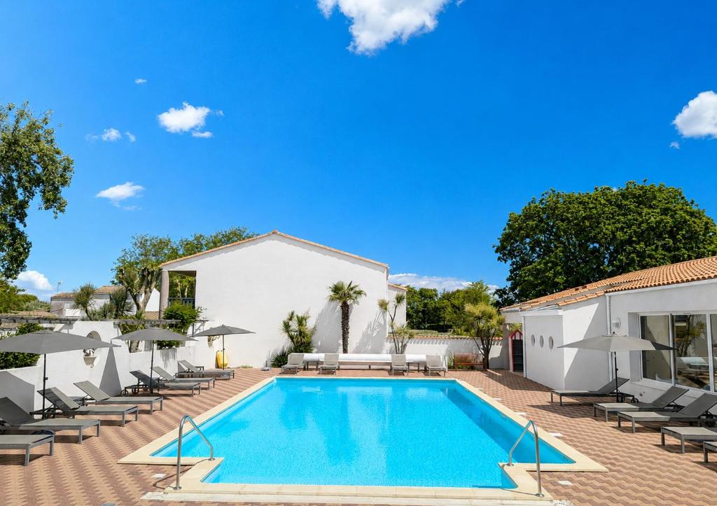 a swimming pool with lounge chairs and umbrellas at Hotel L'Oceane in La Cotinière