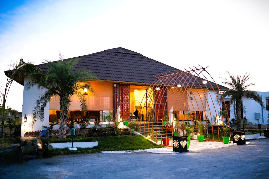 a house with palm trees in front of it at Yadus By Alcor in Bīsalpur