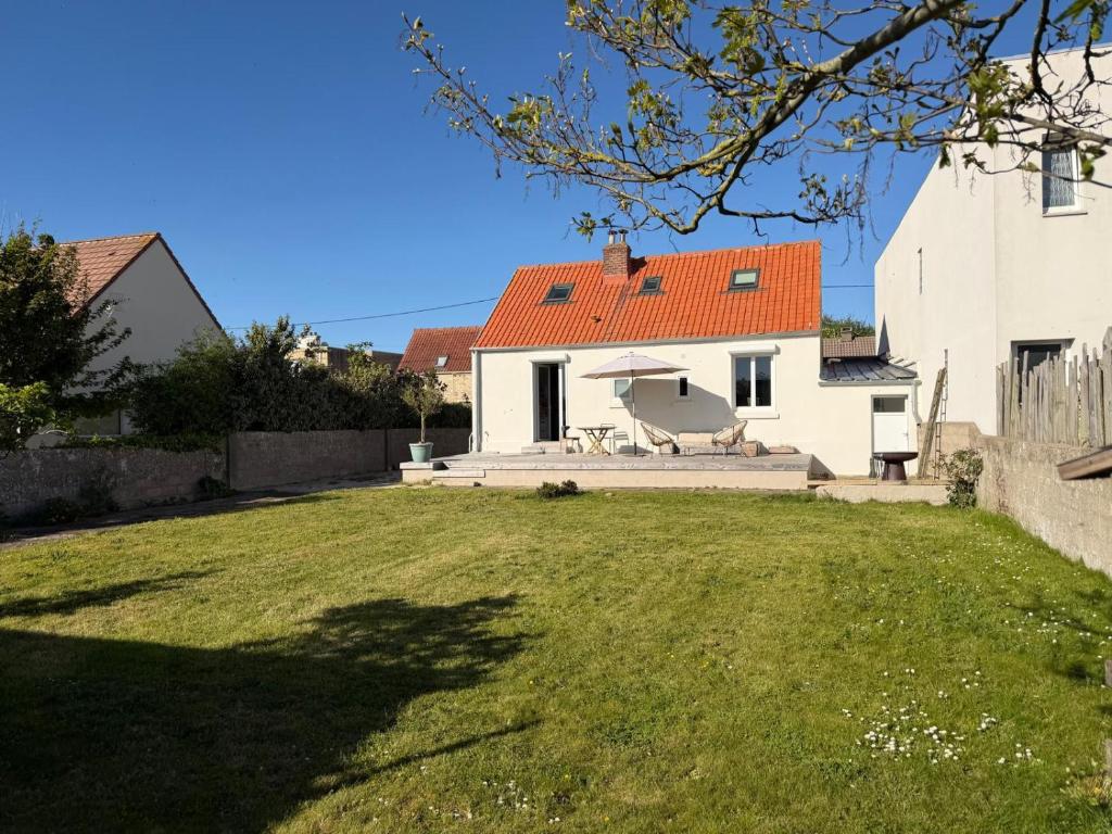 a white house with a red roof and a yard at Maison semi individuelle avec jardin in Ambleteuse