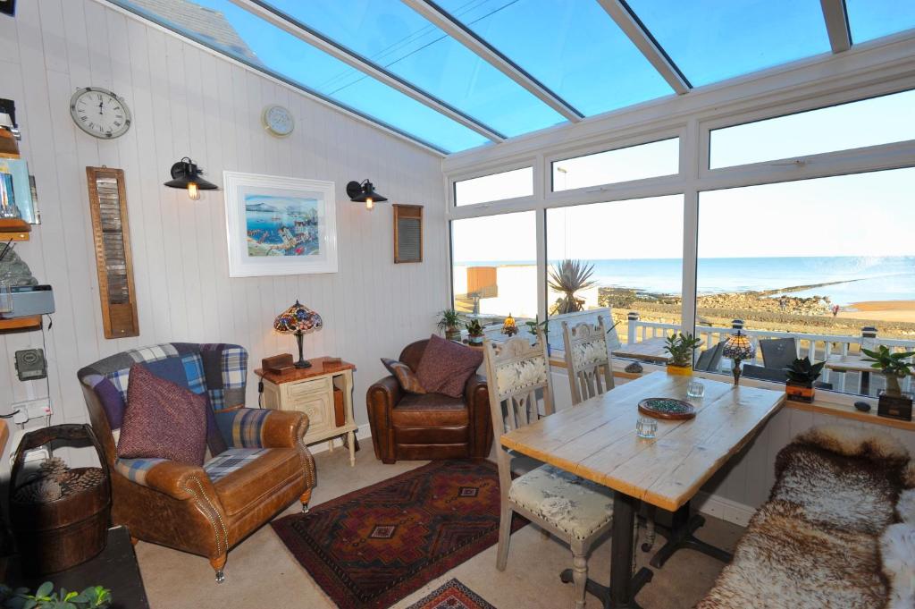 a living room with a table and a view of the ocean at Sea View Guest House in Benllech