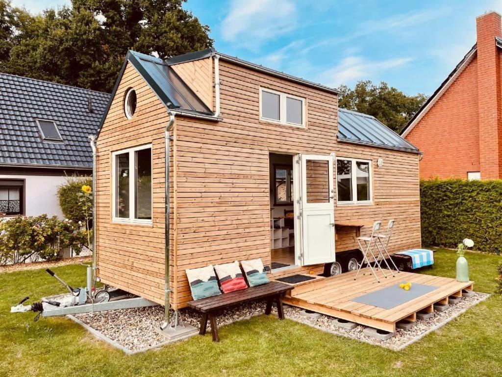 a tiny house with a deck in a yard at TINY HOUSE FLEESENSEE mit eigenem Garten und nur wenige Meter vom Seeufer in Unter Göhren