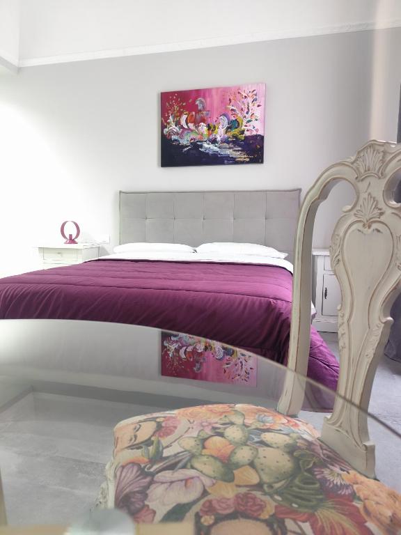 a bedroom with a bed with purple sheets and a chair at Le stanze del Corso in Monreale