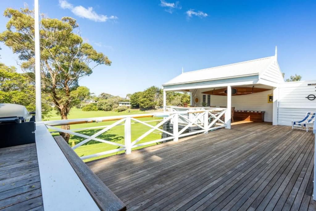 a large deck with a white building and a house at Parkview Cottage Portsea in Portsea
