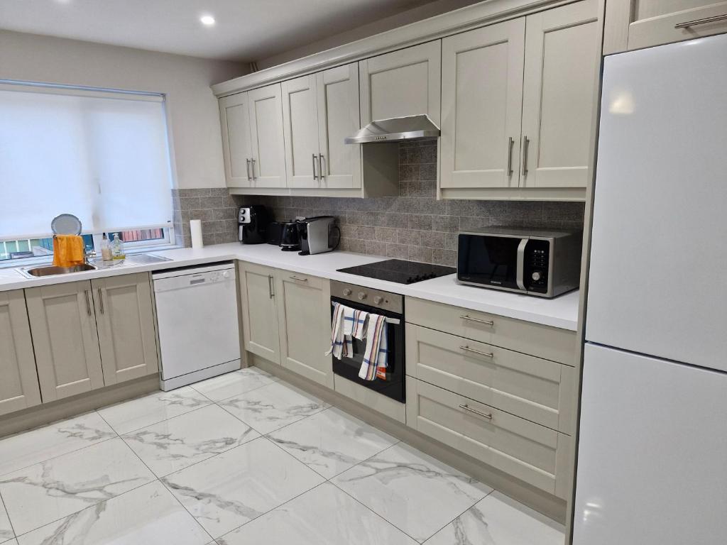 a kitchen with white cabinets and a stove top oven at Townhouse Sleeps 8 - Garden Wifi Free Parking in Belmullet