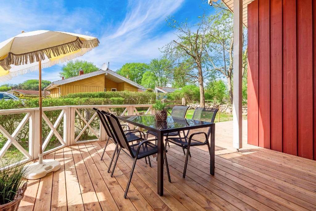 a table and chairs on a wooden deck with an umbrella at Strandblick - Dorf 1 Ferienhaus 07 in Priwall