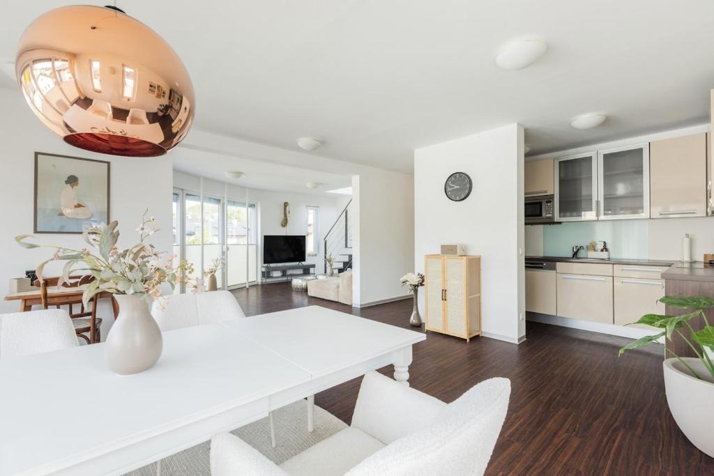 a kitchen and living room with a white table and chairs at Helles Penthouse mit Dachterrasse & Bergblick in Mondsee