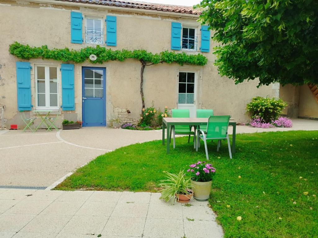 a table and chairs in front of a house with blue shutters at Le Logis de bouillé in Bouillé-Courdault