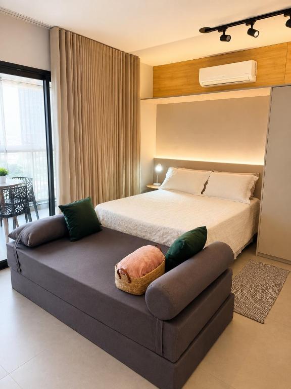 a bedroom with a bed and a couch in it at Studio na Av Esmeraldas com garagem in Marília