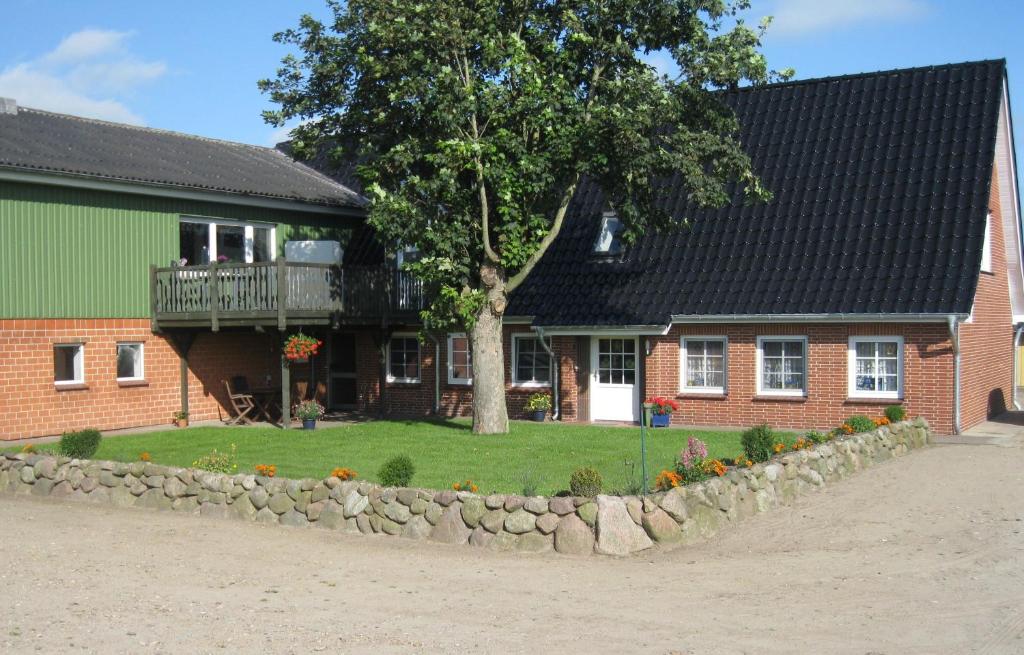 a house with a tree in front of it at Clausen - Ferienwohnung mit 4 Schlafzimmern, 2 Bädern, Aufenthaltsraum mit Kamin und Garten in Janneby