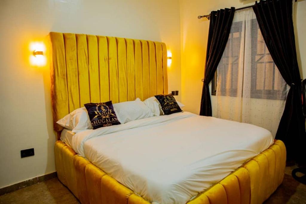 a bedroom with a large bed with a yellow headboard at Shugaland hotel and lounge in Ibadan