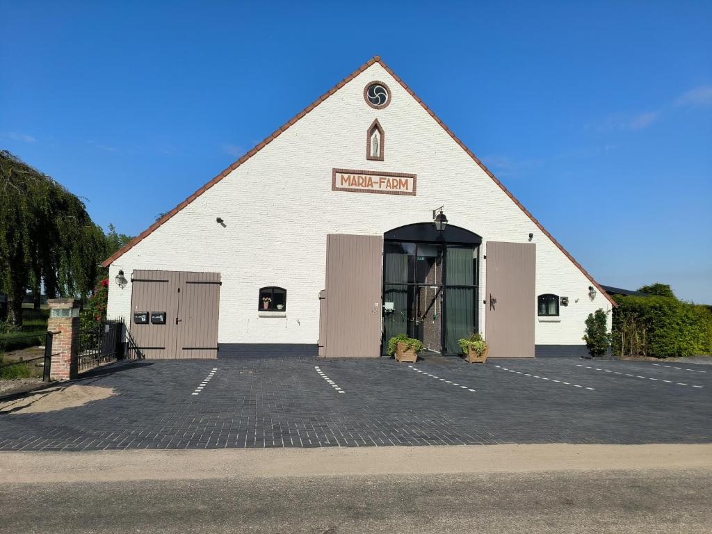 a white barn with a large door in a parking lot at Mariafarm Boutique Hotel in Zevenbergen