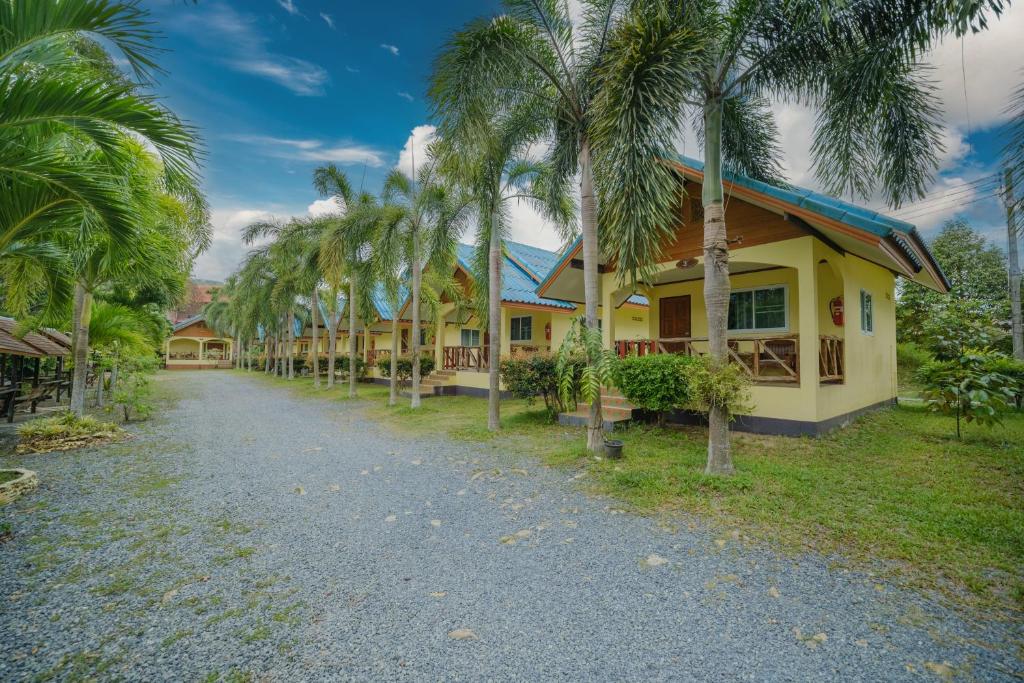 a row of palm trees in front of a house at Baanrimklong bungalow in Ko Chang