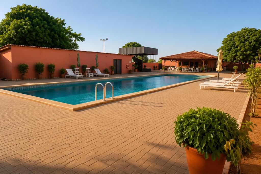 a swimming pool with two plants in front of a building at Viana Hotel in Luanda