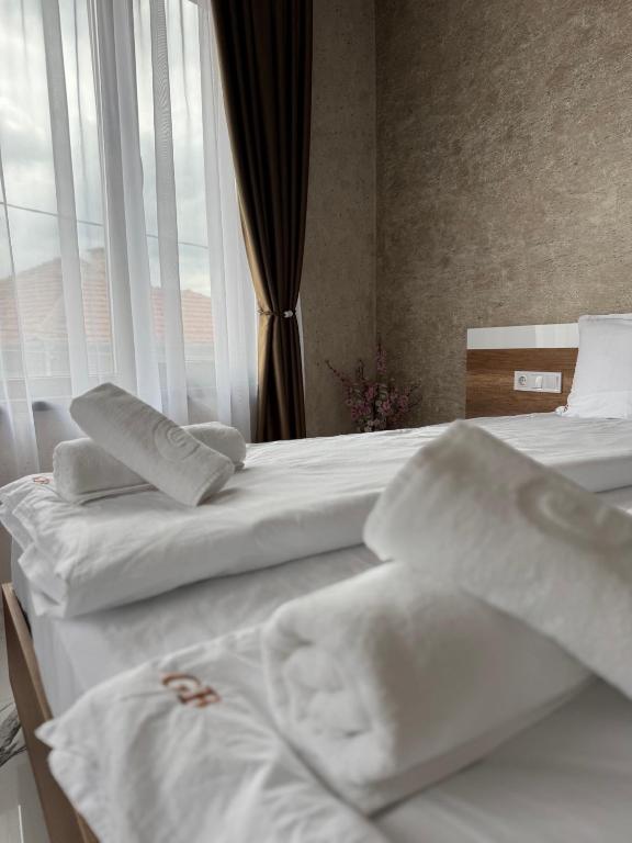 two beds with white sheets in a room with a window at Стаи за гости- Maria Elegance in Pavel Banya