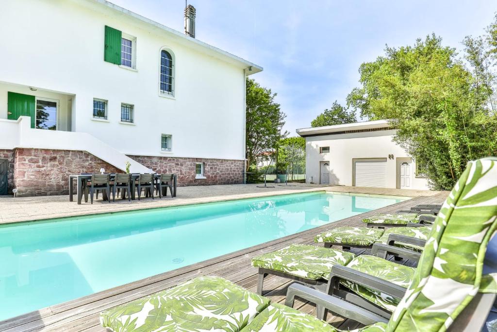 a swimming pool with lounge chairs and a house at Maroutine - AC - Piscine & Tennis in Labouheyre