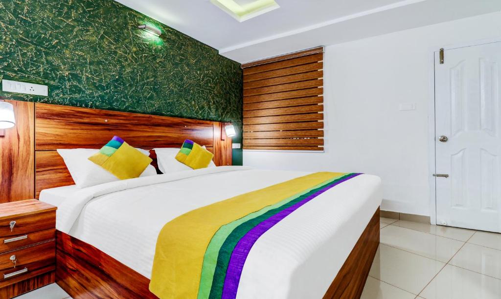 a bedroom with a large white bed with a wooden headboard at Itsy Hotels Dew Dreams in Cochin