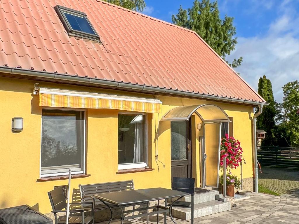 a yellow house with an orange roof with a table and chairs at Luzie's Hus in Freest