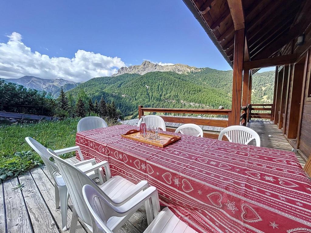 a table and chairs on a deck with a view of mountains at Chalet Face aux Etoiles in Molines-en-Queyras