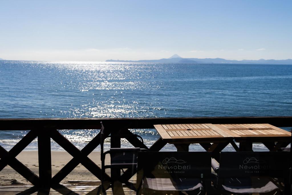 a picnic table and chairs on the beach near the water at Nesoberi VILLA TAKASU in Kanoya