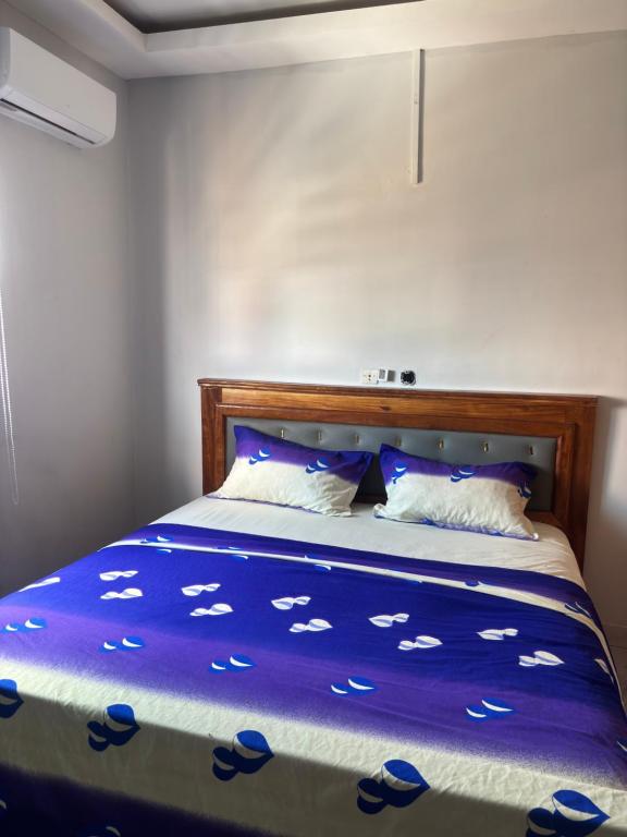 a bed with a blue comforter and two pillows at Résidence meublée du boss in Abidjan