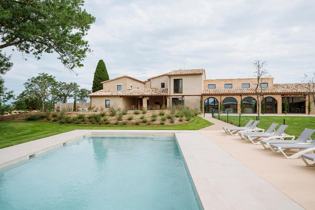a pool in front of a house with lounge chairs at Hotel Mas Vidal Vilafreser in Vilademuls