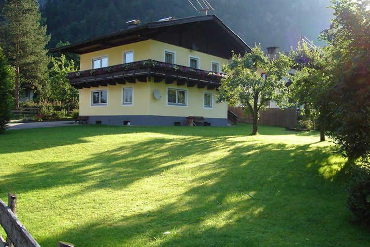 a large yellow house with a large yard with a grassy field at Ferienwohnung Jirkal in Sankt Martin bei Lofer