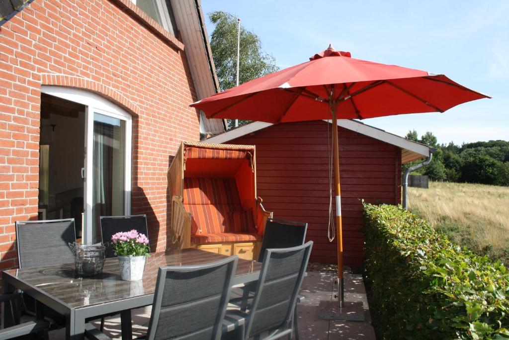 a patio with a table and a red umbrella at Beeck - FeWo mit Terrasse und Strandkorb in Oeversee