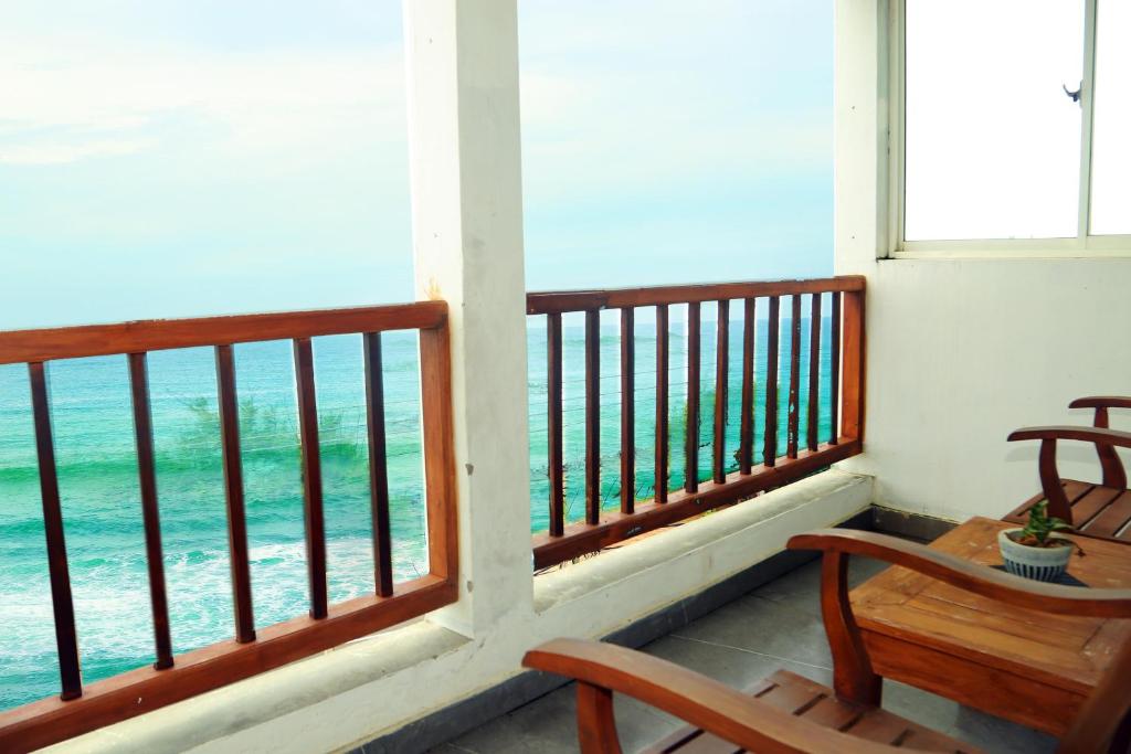 a balcony with a table and chairs and the ocean at Cozy Cocos Midigama in Ahangama