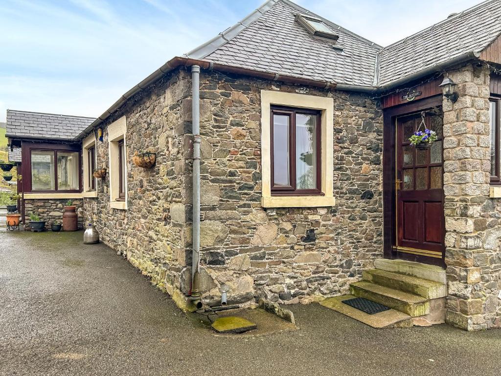 a stone house with a wooden door and stairs at Bothy Cottage - Uk51350 in Peebles