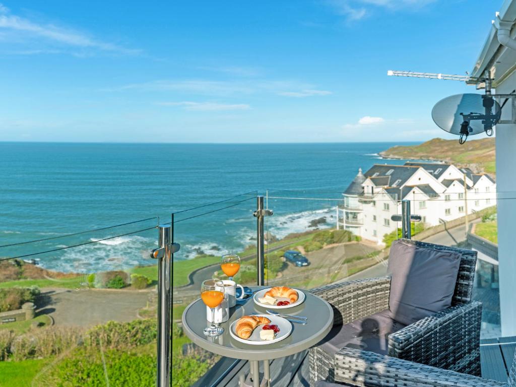a table with food and drinks on a balcony with the ocean at Sunset Beach - Uk42994 in Woolacombe