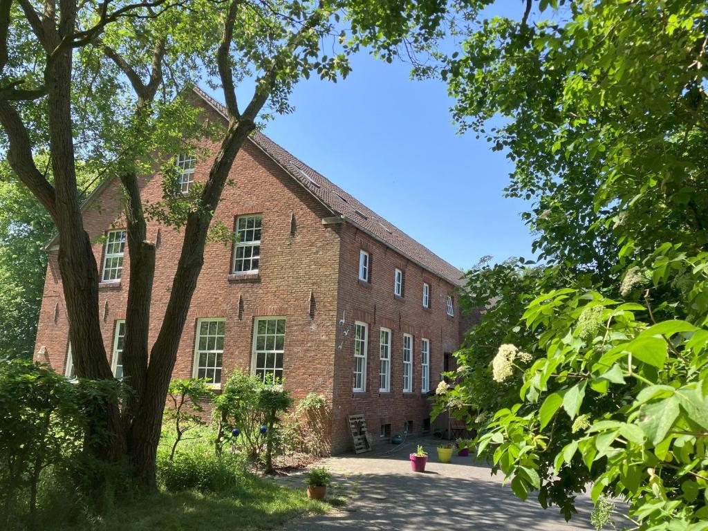 an old brick building with trees in front of it at Gulfhof Friedrichsgroden in Carolinensiel
