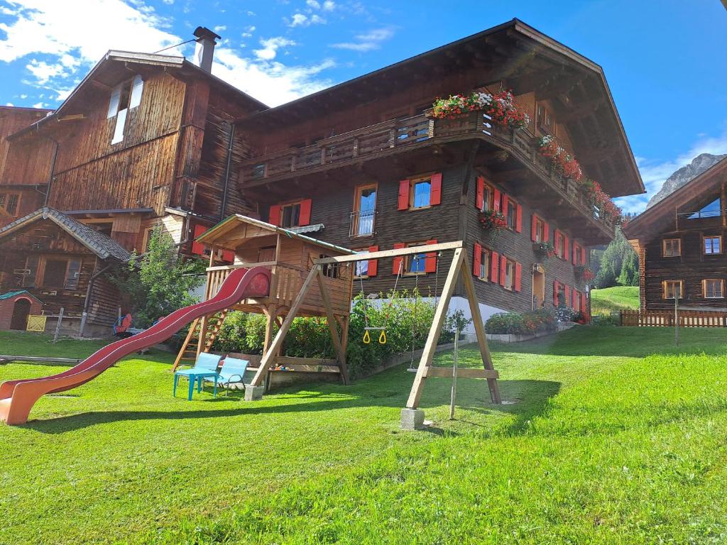 a playground in front of a house with a slide at Haus Peintner in Tannheim