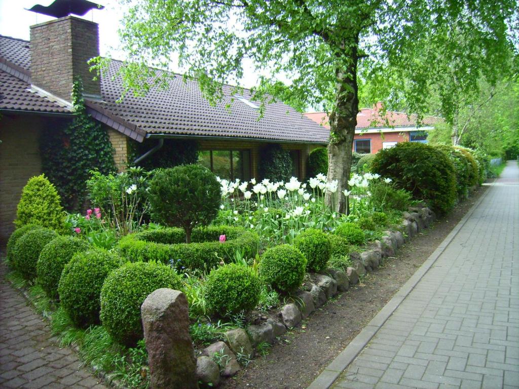 a garden with white flowers and bushes next to a building at Ferienwohnung Diena - Unterkunft mit toller Ausstattung und zwei Terrassen in Tarp